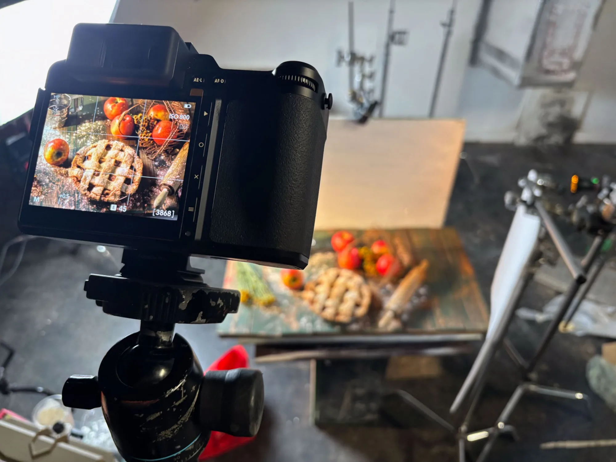 Camera on a tripod with its monitor framing a plated dish on the set table - Raging Bull Food Photography